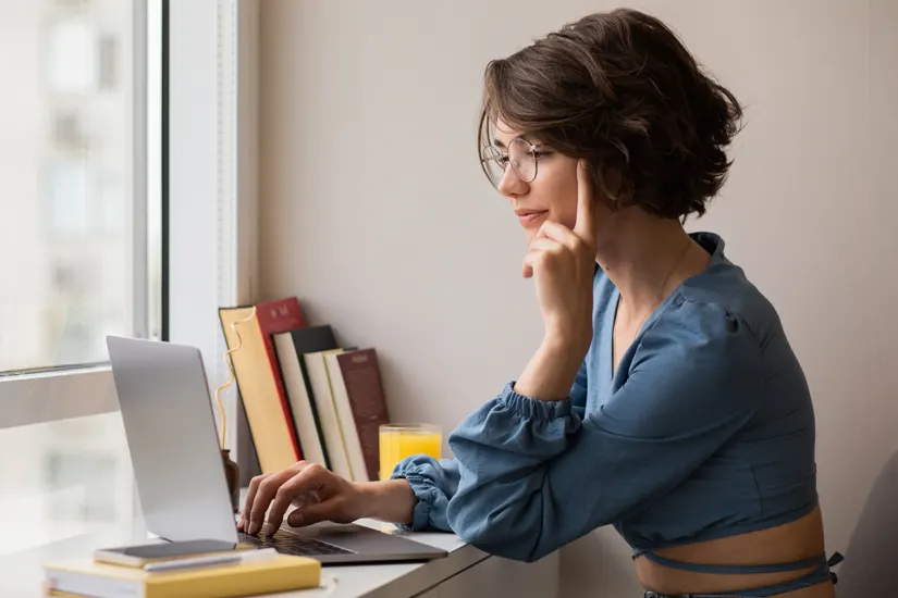 Mujer editando en su portátil junto a una ventana — Tregolam
